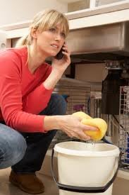 Homeowner with a sponge cleaning water in basement